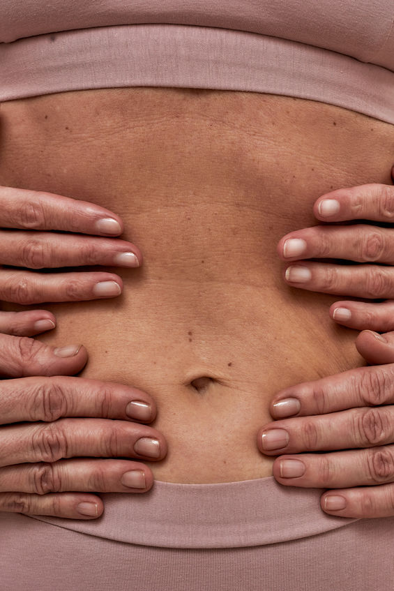 Palms of two people hugging a naked stomach of a woman wearing pink underwear