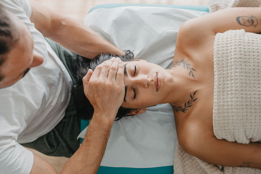 top view of a therapist with his hands on the forehead of a young woman in Reiki therapy. Health